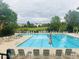 Large community pool with plentiful lounge chairs, tables, green grass, and shady trees at 8114 Briar Ridge Dr, Castle Pines, CO 80108