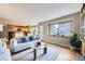 Bright living room featuring a cozy sofa, wood floors, an open kitchen and ample natural light from a large window at 5784 W 81St Cir, Arvada, CO 80003