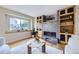 Cozy living room with a modern fireplace, built-in shelving, a round coffee table, and a large window view at 5784 W 81St Cir, Arvada, CO 80003