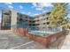 Apartment complex with multi-level balconies, secured pool area, and ample parking under a sunny sky at 33 N Corona St # 401, Denver, CO 80218