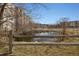 A tranquil pond is surrounded by bare trees and a rustic split rail fence at 7770 W 38Th Ave # 108, Wheat Ridge, CO 80033