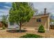 Side view of the home, featuring a brick exterior, a healthy tree, and tasteful low-maintenance landscaping at 7828 Florado St, Denver, CO 80221