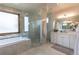 Elegant bathroom featuring marble tiling, a glass-enclosed shower, and a soaking tub with tile surround at 5767 Pelican Shores Dr, Longmont, CO 80504