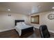 Cozy bedroom with dark wood floors, black bed frame, and a charming window with shutters at 5767 Pelican Shores Dr, Longmont, CO 80504