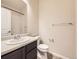 Bright bathroom featuring a vanity with a modern sink, toilet, and a shower with white tiled walls at 600 E Dry Creek Pl, Littleton, CO 80122