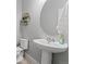 Cozy half bathroom featuring a pedestal sink, round mirror, and decorative floating shelves at 3344 Evening Pl, Castle Rock, CO 80109
