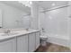 Bright bathroom featuring double sink vanity with granite counter, large mirror, and white tub and shower at 9153 Truckee Ct, Commerce City, CO 80022