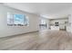 Spacious living room with large windows, light wood-look flooring, and an open floor plan to the kitchen at 9153 Truckee Ct, Commerce City, CO 80022