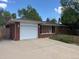 Charming single-story brick home featuring a two-car garage and a well-maintained front yard with mature trees at 1740 S Estes St, Lakewood, CO 80232