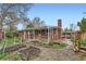 Exterior view of a brick home with a covered porch and garden beds in the backyard at 1740 S Estes St, Lakewood, CO 80232