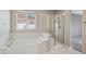 Bright bathroom with a tub, a tiled shower, and a large window, offering a tranquil retreat at 7852 S Addison Way, Aurora, CO 80016
