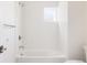 Well-lit bathroom with a white tiled shower/tub featuring a window for natural light at 2321 S Acoma St, Denver, CO 80223