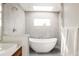 Bright bathroom featuring a modern soaking tub, tiled walk-in shower, and a window at 2321 S Acoma St, Denver, CO 80223