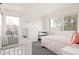 A cozy bedroom featuring a twin bed, a crib, and white walls with windows at 2321 S Acoma St, Denver, CO 80223