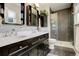 Modern bathroom featuring double sink vanity, framed mirrors, shower with glass door, and gray wood-look flooring at 13695 W 67Th Cir, Arvada, CO 80004