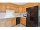 Kitchen features light oak cabinets, tile backsplash, black appliances, and tile flooring at 2410 S Lima St, Aurora, CO 80014