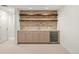 A basement bar features custom cabinets, a beverage refrigerator and a beautiful brick backsplash with wood shelves at 2056 S Ogden St, Denver, CO 80210