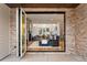 A spacious living room is seen through an open folding glass wall with a fireplace, couch and dining area at 2056 S Ogden St, Denver, CO 80210