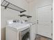 Bright laundry room featuring a washer and dryer with shelving above and a door leading outside at 14938 Clayton St, Thornton, CO 80602