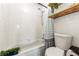 Bright bathroom with white tile shower and tub combo with wooden shelving for storage at 5745 W Atlantic Pl # 108, Lakewood, CO 80227