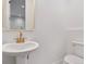 Clean white powder room featuring a modern vanity, gold mirror, and toilet at 1250 Yates St, Denver, CO 80204