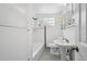 Bright, clean bathroom with white tile, a pedestal sink, and a bathtub with glass block window at 925 Fulton St, Aurora, CO 80010