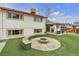 Spacious backyard with artificial turf, stone fire pit, bench seating, and covered patio at 12079 E Louisiana Ave, Aurora, CO 80012
