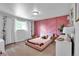 Bedroom with pink accent wall, plush carpet, a window, and floral accents at 12079 E Louisiana Ave, Aurora, CO 80012