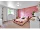 Bedroom with pink accent wall, plush carpet, a window, and floral accents at 12079 E Louisiana Ave, Aurora, CO 80012