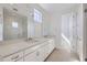 Bathroom featuring double sinks, white cabinets, and a glass shower at 657 Harness St, Erie, CO 80516
