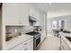 Modern kitchen featuring white cabinets, stainless steel appliances, and a light gray backsplash at 657 Harness St, Erie, CO 80516