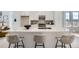 Kitchen island with seating featuring white cabinets, marble countertop, and stainless steel sink at 657 Harness St, Erie, CO 80516
