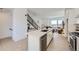 Modern kitchen with white cabinets, quartz countertops, stainless appliances, open to the living area with staircase at 657 Harness St, Erie, CO 80516