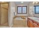 Luxurious bathroom with a separate glass-enclosed shower and a relaxing soaking tub by a window at 8053 E Maple Ave, Denver, CO 80230