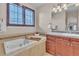 Serene bathroom featuring a soaking tub, dark wood cabinets, and shuttered windows for natural light at 8053 E Maple Ave, Denver, CO 80230