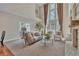 Bright living room featuring soaring ceilings, large windows, fireplace, and neutral color palette at 8053 E Maple Ave, Denver, CO 80230