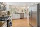 Well-lit kitchen featuring stainless steel appliances, granite counters, white cabinetry, and hardwood floors at 9921 Spring Hill Pl, Highlands Ranch, CO 80129