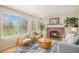 Sunlit living room with a cozy brick fireplace, large windows, and comfortable seating area at 9921 Spring Hill Pl, Highlands Ranch, CO 80129
