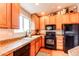 Well-lit kitchen featuring wooden cabinets, granite countertops, and black appliances at 4730 Copeland Cir # 204, Highlands Ranch, CO 80126