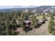 An aerial view showcasing the home and its adjacent outbuildings amidst a dense forest setting at 25392 Westridge Rd, Golden, CO 80403