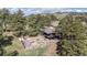 Aerial view of lovely home with a backyard, deck, detached garage, and bordered by mature pine trees at 25392 Westridge Rd, Golden, CO 80403