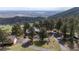 Peaceful aerial view of a home nestled among mature trees with long driveway and mountain vista in the distance at 25392 Westridge Rd, Golden, CO 80403