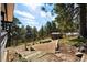 View of wood stairs leading to the backyard, featuring storage shed, gas tank, and mature trees at 25392 Westridge Rd, Golden, CO 80403