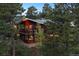 Two-story home with a red-toned wood exterior and large windows, nestled among green trees at 25392 Westridge Rd, Golden, CO 80403