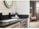 Stylish bathroom featuring a modern vanity with black countertop, a white sink and shiplap walls, and a decorative mirror at 14110 Pastel Ln, Parker, CO 80134