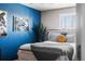 Bedroom featuring a striking blue accent wall, whitewashed wood bed frame, and shuttered window at 14110 Pastel Ln, Parker, CO 80134