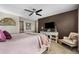 Stylish bedroom with a brown accent wall, a decorative console with mounted TV, and soft color palette at 14110 Pastel Ln, Parker, CO 80134