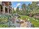 Backyard with a stone fire pit surrounded by trees and lush landscaping, creating a relaxing outdoor space at 1105 Northwood Ln, Castle Rock, CO 80108