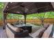 A backyard patio with a metal gazebo, cushioned seating, a fire pit, and a wood fence, offering a cozy outdoor retreat at 2746 Geneva St, Denver, CO 80238