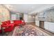 Finished basement with red sectional sofa, decorative rug, and kitchenette area with stainless steel appliances at 2746 Geneva St, Denver, CO 80238
